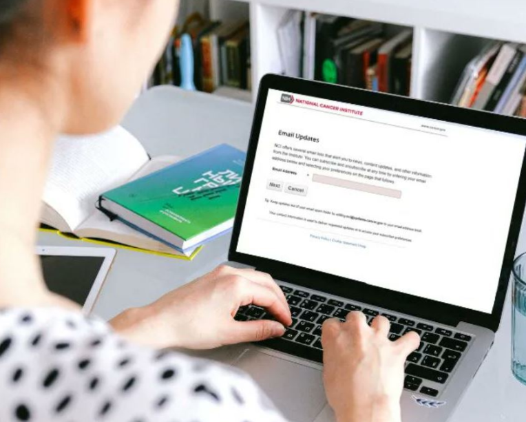 A seated woman typing on her laptop's keyboard.