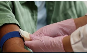 A seated patient getting measured for toxicity index by a medical assistant wearing gloves..