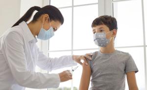 A young male patient receiving a vaccination shot in the arm.