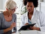 Female doctor speaking with an elderly female patient while looking at test results.