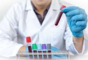 An image of lab technician placing a test tube in a rack.